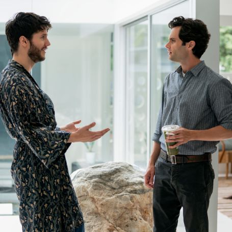 joe holding a green juice bottle and forty standing infront of him wearing a robe 